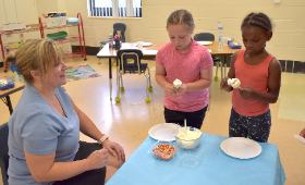 Denise Smith, left, of Sweet Cheeks Bakery helps Rock Hall Elementary School Acceleration Academy students make cake pops similar to the truffula trees in "The Lorax."